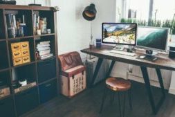 Gezonde werkplek met houten bureau, dubbele monitoren, natuurlijk licht en ergonomische inrichting