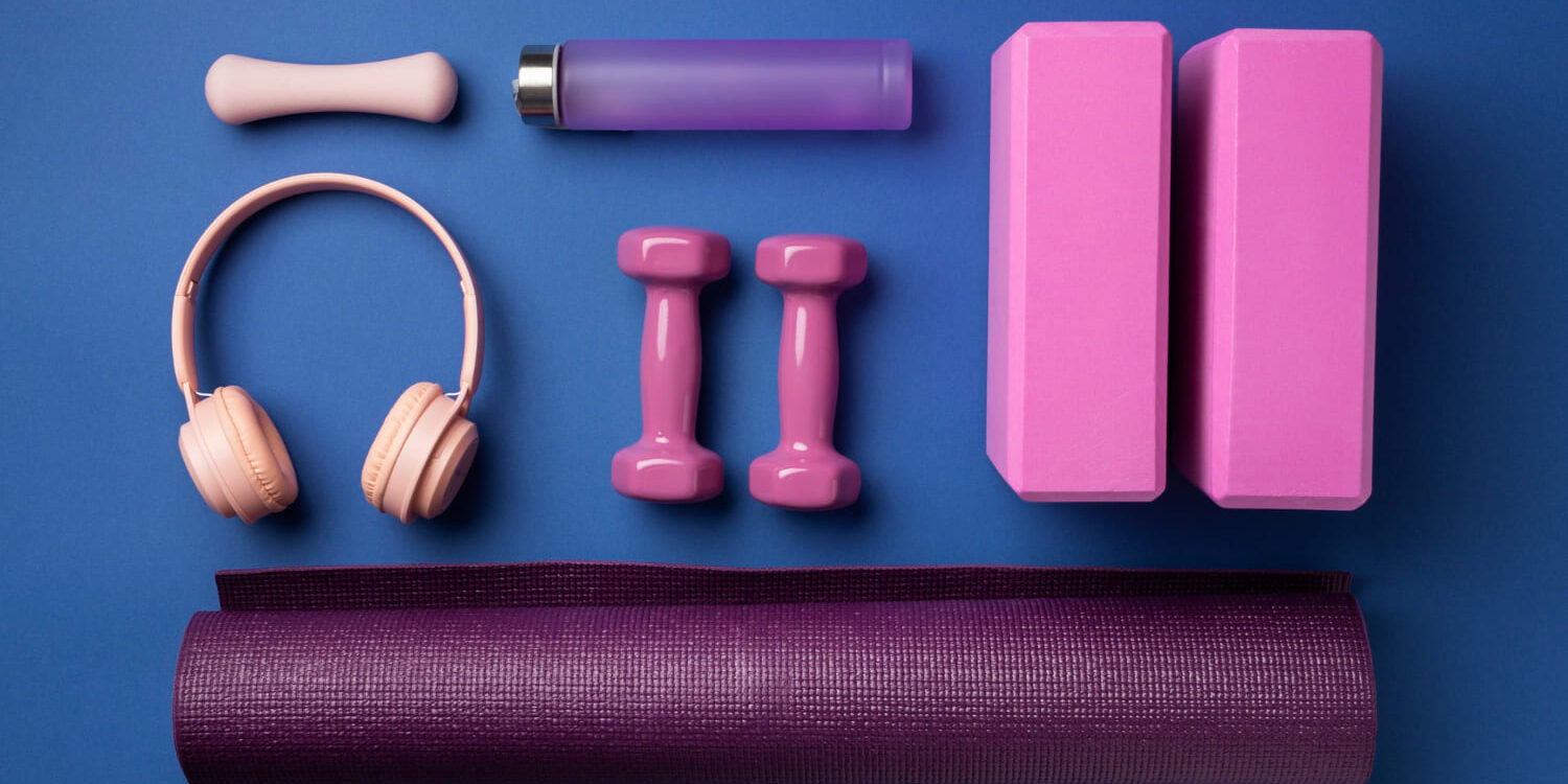 Sportaccessoires voor herstel na het sporten, zoals dumbbells, yogamat en foamblok op blauwe achtergrond