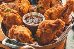 Krokante gefrituurde kipstukken geserveerd met barbecuesaus in een metalen schaal