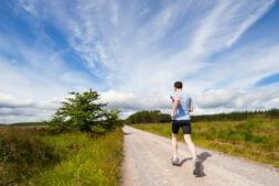 Man loopt hard op een lang, recht bospad onder een open lucht, perfect moment voor lange afstand lopen