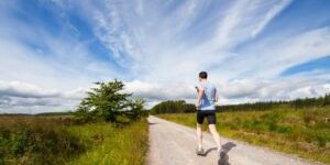 jenny-hill-mQVWb7kUoOE-unsplash-300×169-1 Man loopt hard op een lang, recht bospad onder een open lucht, perfect moment voor lange afstand lopen