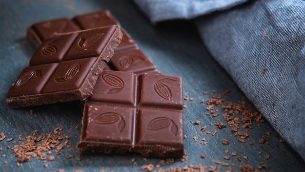 Pure eerlijke chocolade Eerlijke producten zoals pure chocolade met cacaomotief, op een houten oppervlak met schaafsel
