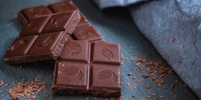 Pure eerlijke chocolade Eerlijke producten zoals pure chocolade met cacaomotief, op een houten oppervlak met schaafsel
