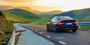 Auto rijdt bij zonsondergang over een rustige bergweg – voorbereiding autorit in praktijk