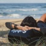 Persoon luistert naar zijn lichaam en ontspant op het strand met uitzicht op zee