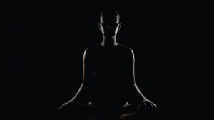 Silhouet van een mediterende vrouw die luistert naar haar lichaam in stilte