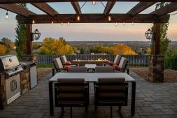 Rustige tuin met houten tuinhuis, zitplek met lichtgrijze tuinmeubels en groene beplanting