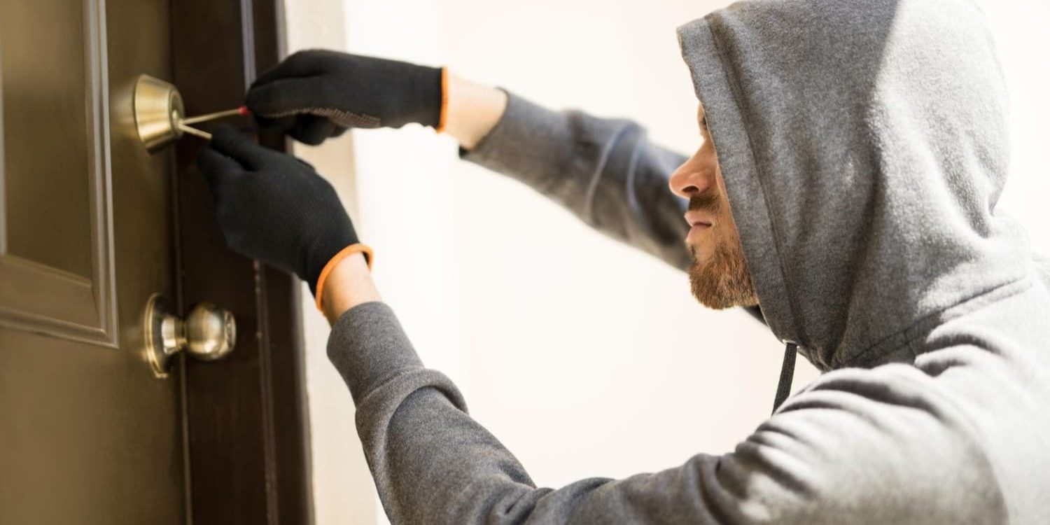 Inbreker probeert slot open te maken wat inbraak impact op veiligheid en vertrouwen laat zien