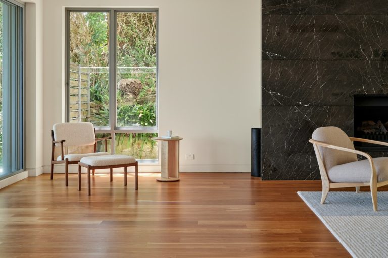 Moderne woonkamer met houten vloer bij allergie, grote ramen, lichte stoelen en klein vloerkleed