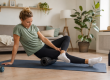 Persoon doet thuis herstel- en mobiliteitsoefeningen op een yogamat tijdens het revalideren van een blessure