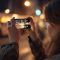Persoon gebruikt smartphone in de avond, terwijl minder schermtijd thuis helpt om bewuster met telefoongebruik om te gaan.
