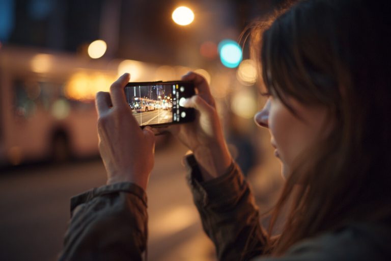 Persoon gebruikt smartphone in de avond, terwijl minder schermtijd thuis helpt om bewuster met telefoongebruik om te gaan.