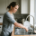 Vrouw houdt haar onderarm onder stromend kraanwater in de keuken om een verbrande huid te koelen