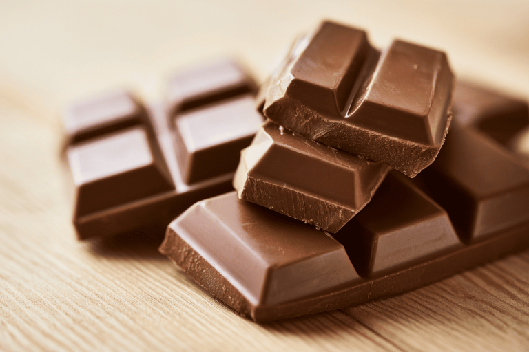 melkchocolade-blokjes-houten-tafel Blokjes melkchocolade op een houten tafel
